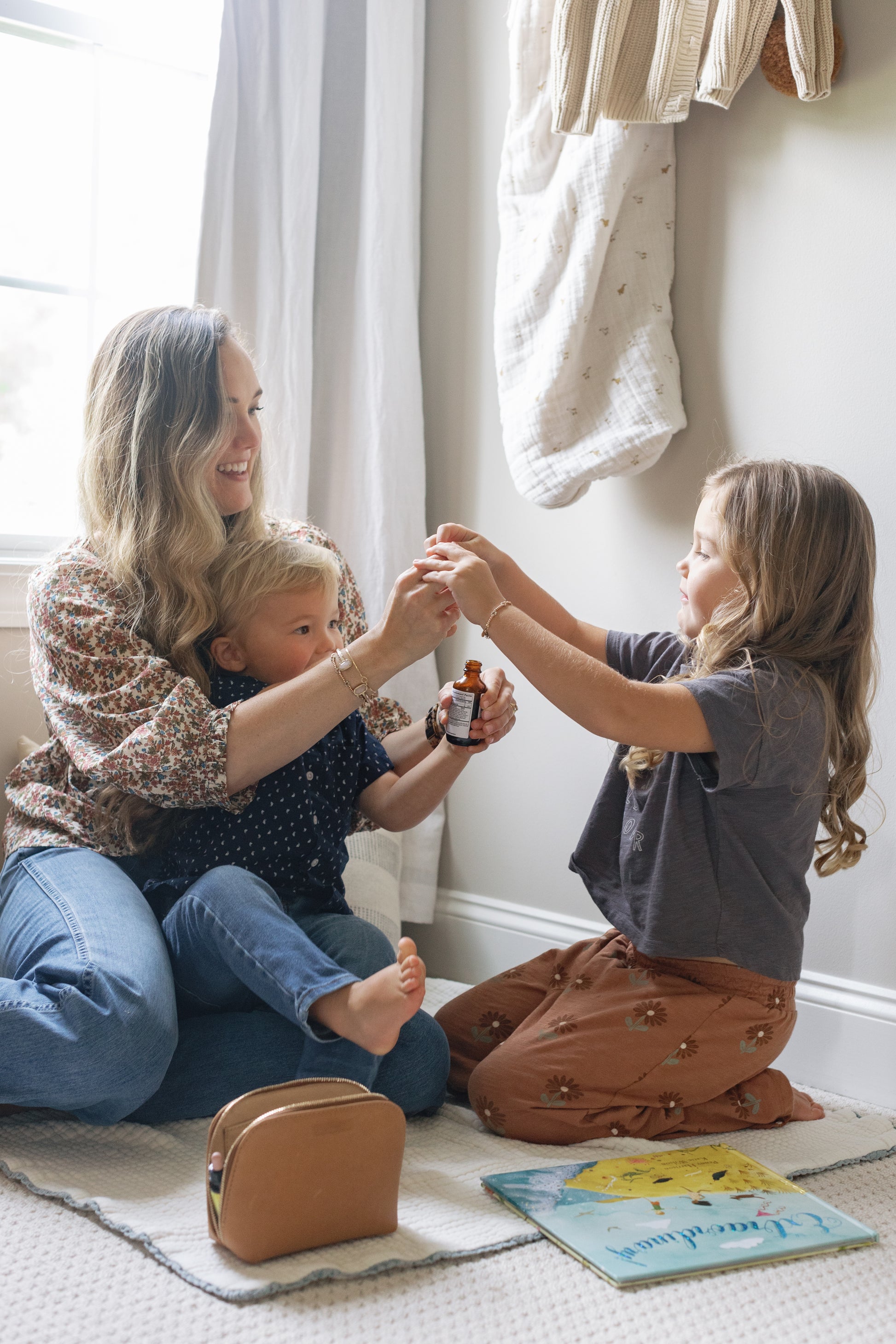 Image of Caroline and her two small children playing with the dropper of the NDF Calm