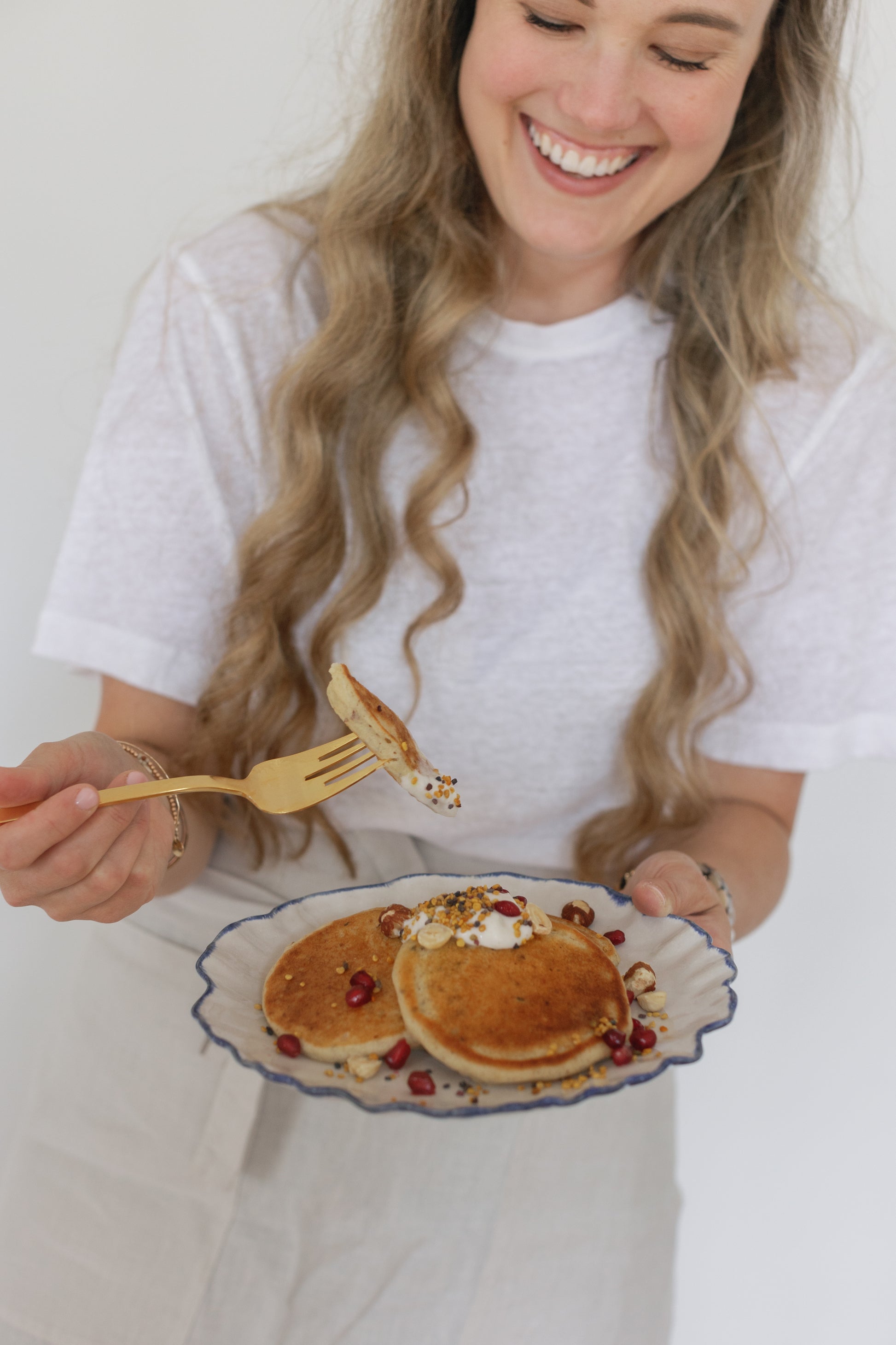 Picture of Caroline smiling and showing, with a fork, a piece of a pancake with the Bee Pollen on top of it