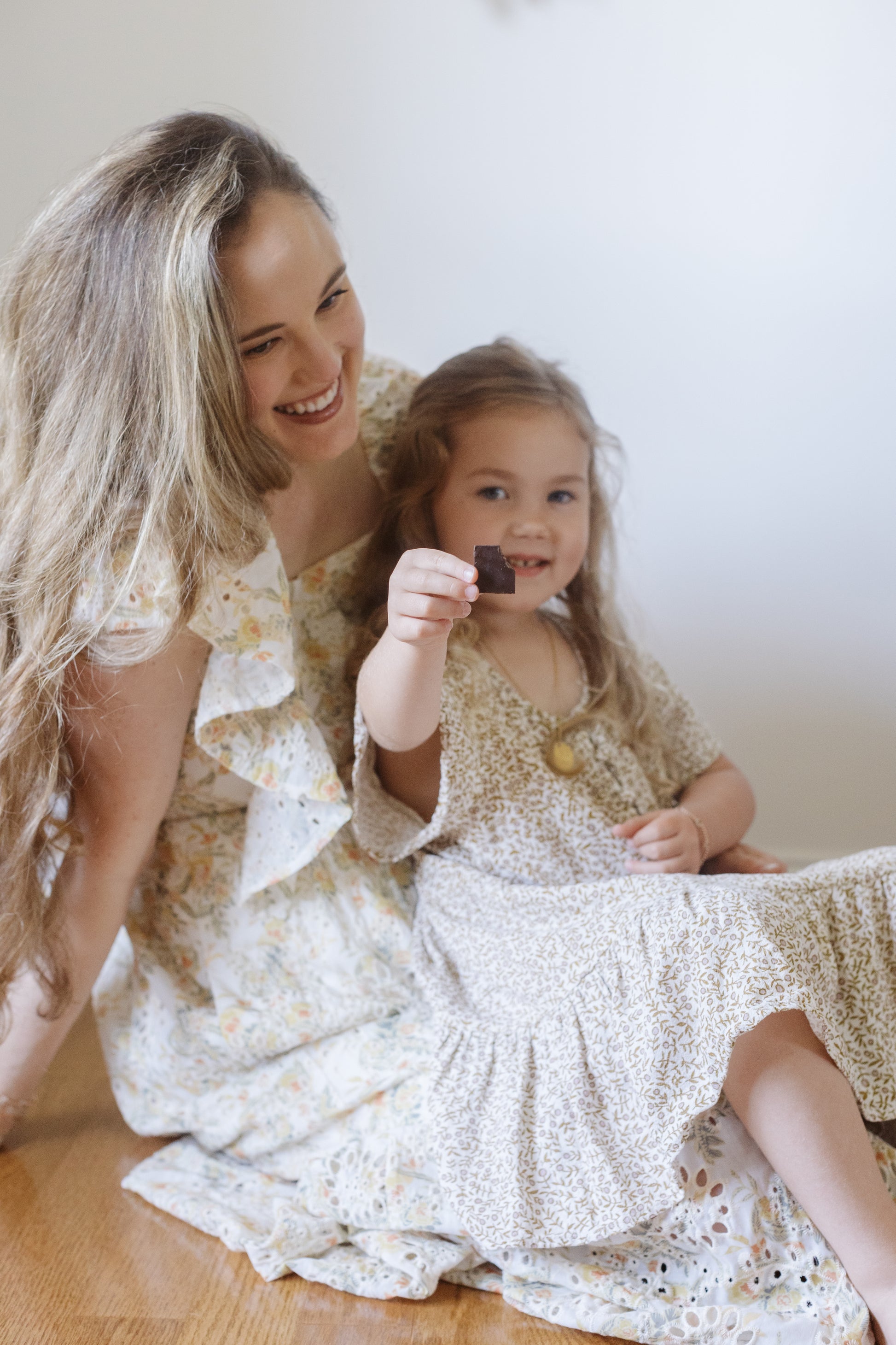 Image of a woman and her daughet smiling while eating the Dark Salty Chocolate and showing it to the camera