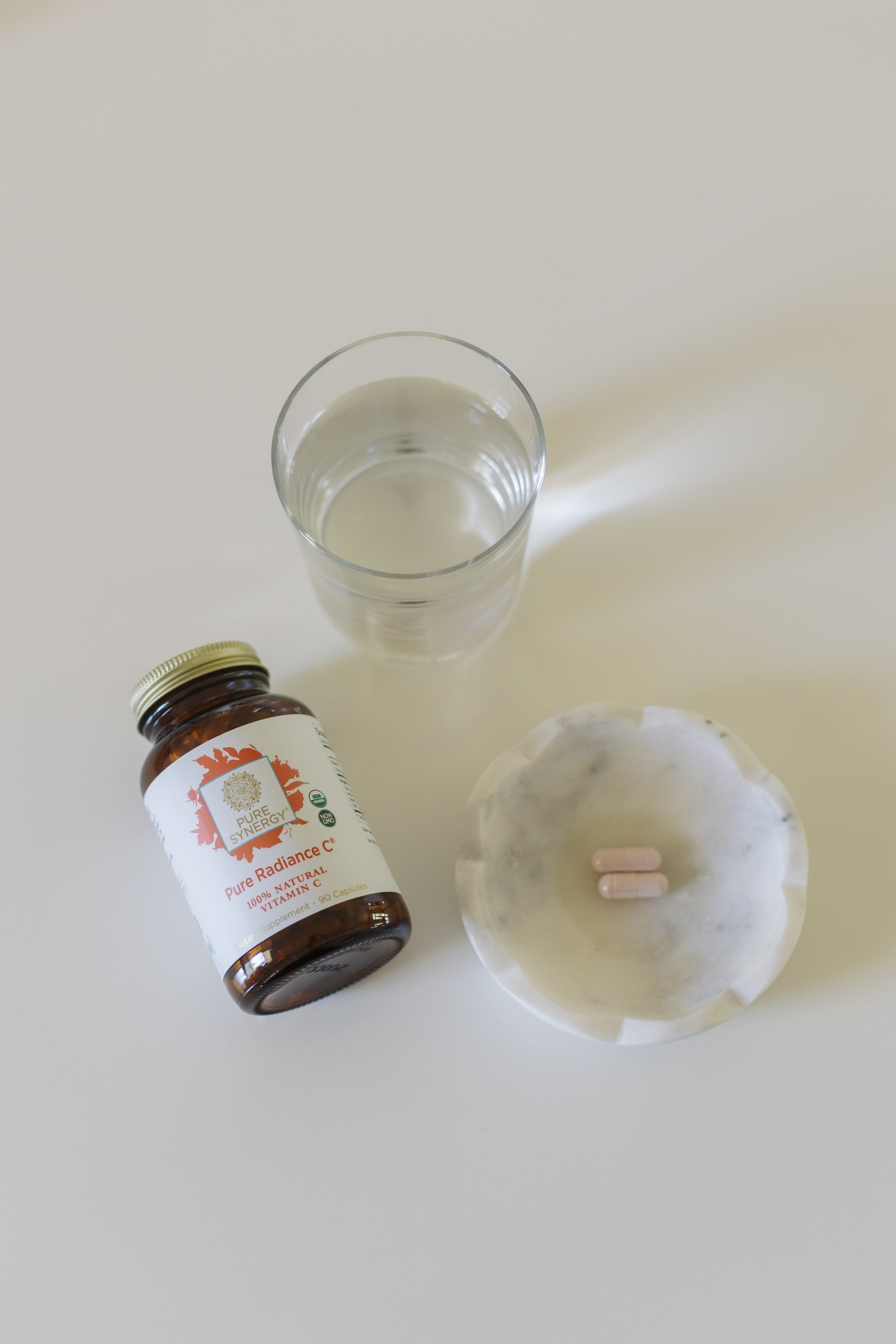 A bottle of Pure Radiance Vitamin C by Pure Synergy on a table.