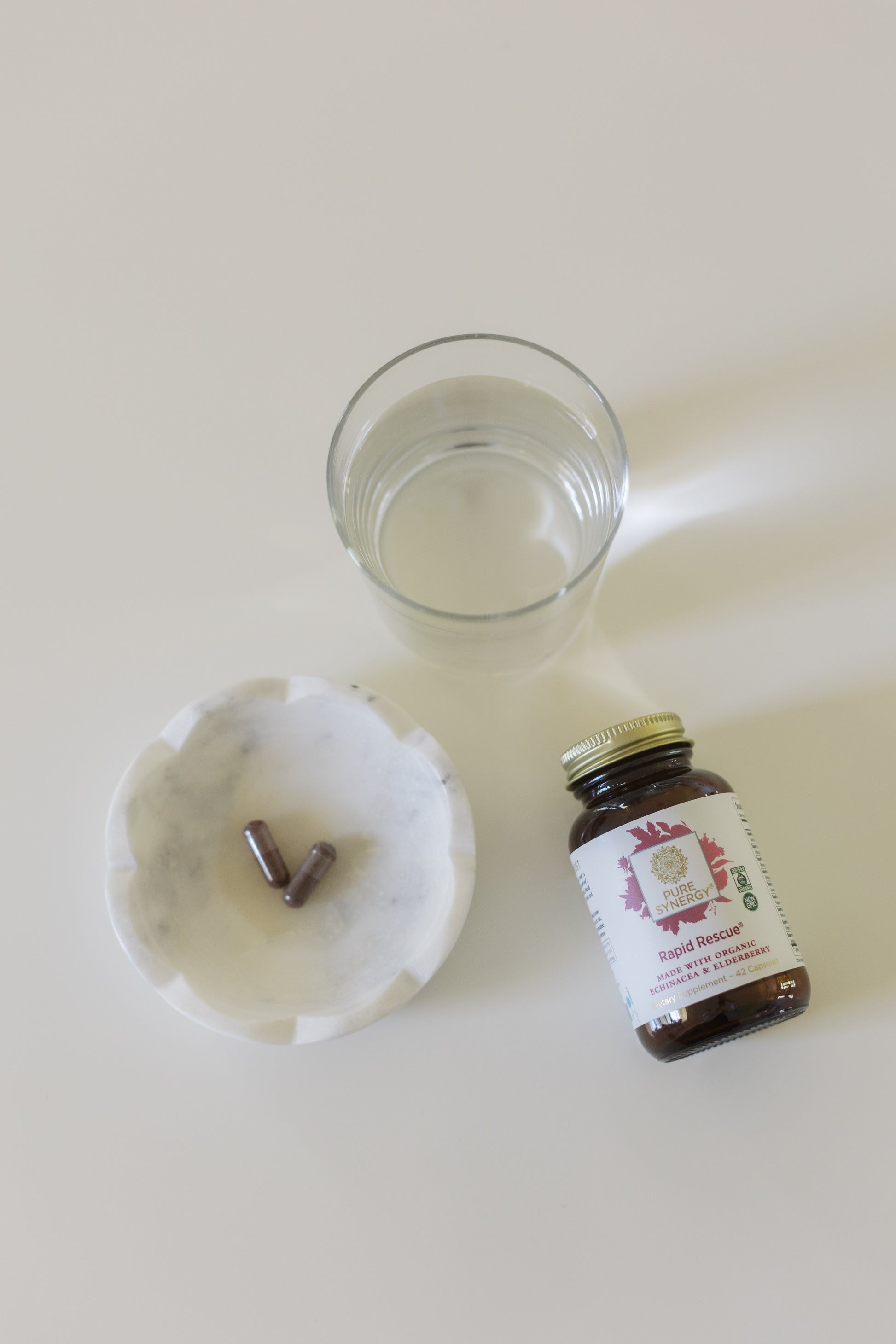 A bottle of Rapid Rescue by Pure Synergy next to a glass of water.