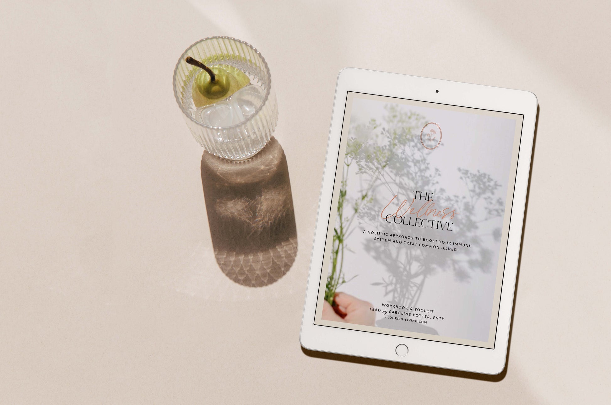 picture of an iPad showing the cover of "The Wellness Collective" with a peach drink on the side
