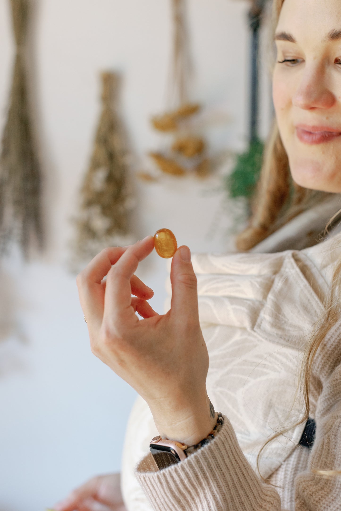 Image of Caroling looking at one tablet of the Soothing Propolis Throat Lozenges