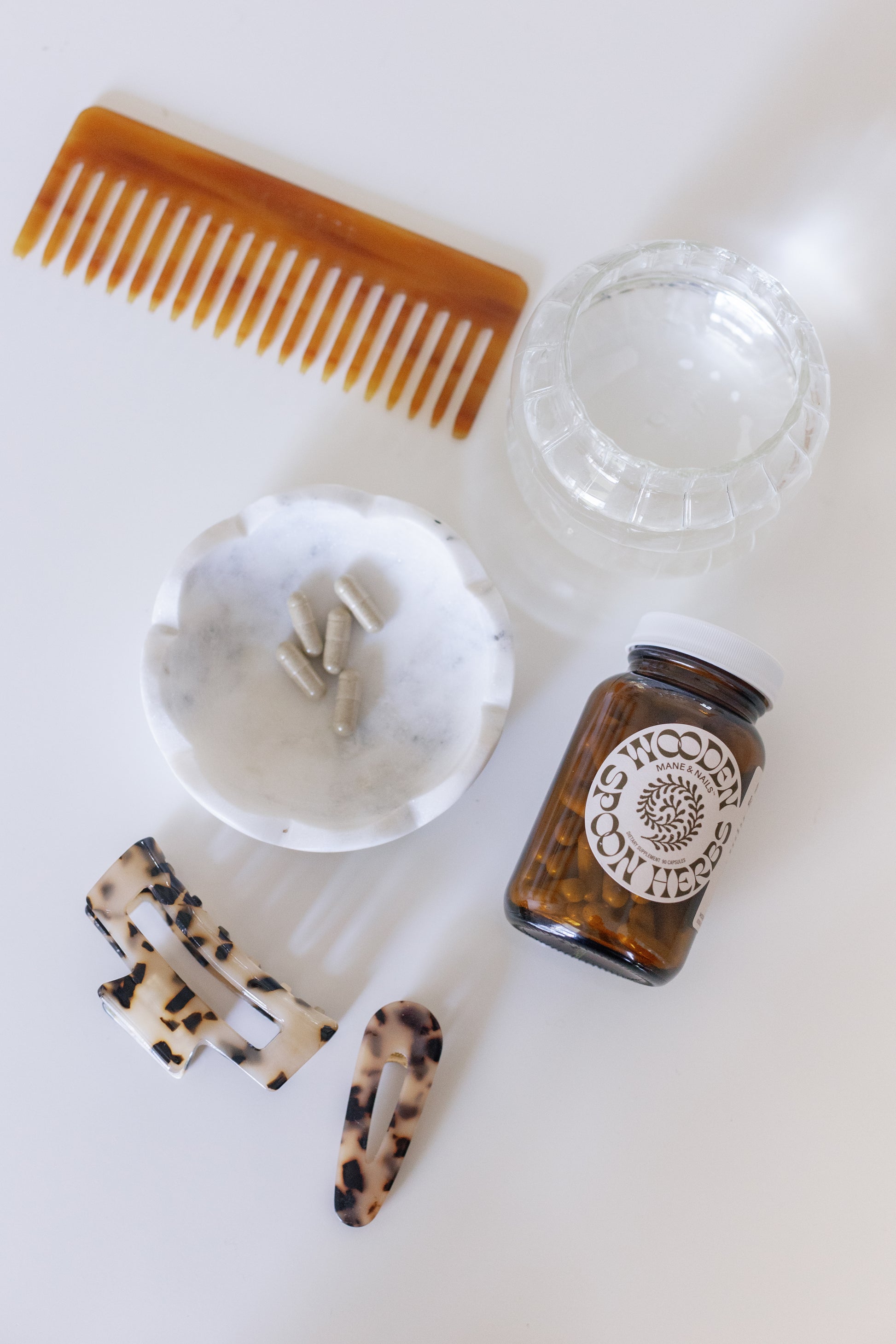Image of the Mane & Nails container on a table with some capsules inside a little white jar