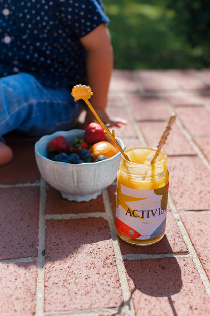 Image of a small child sitting on the flow with an open Manuka Honey can