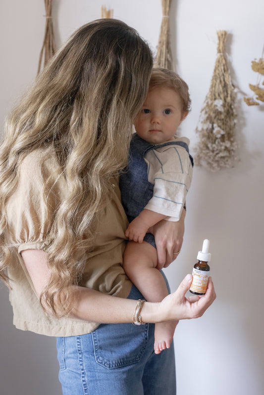 Picture of Caroline and her baby on her lap, with the NDF Infant Colic Relief on her other hand