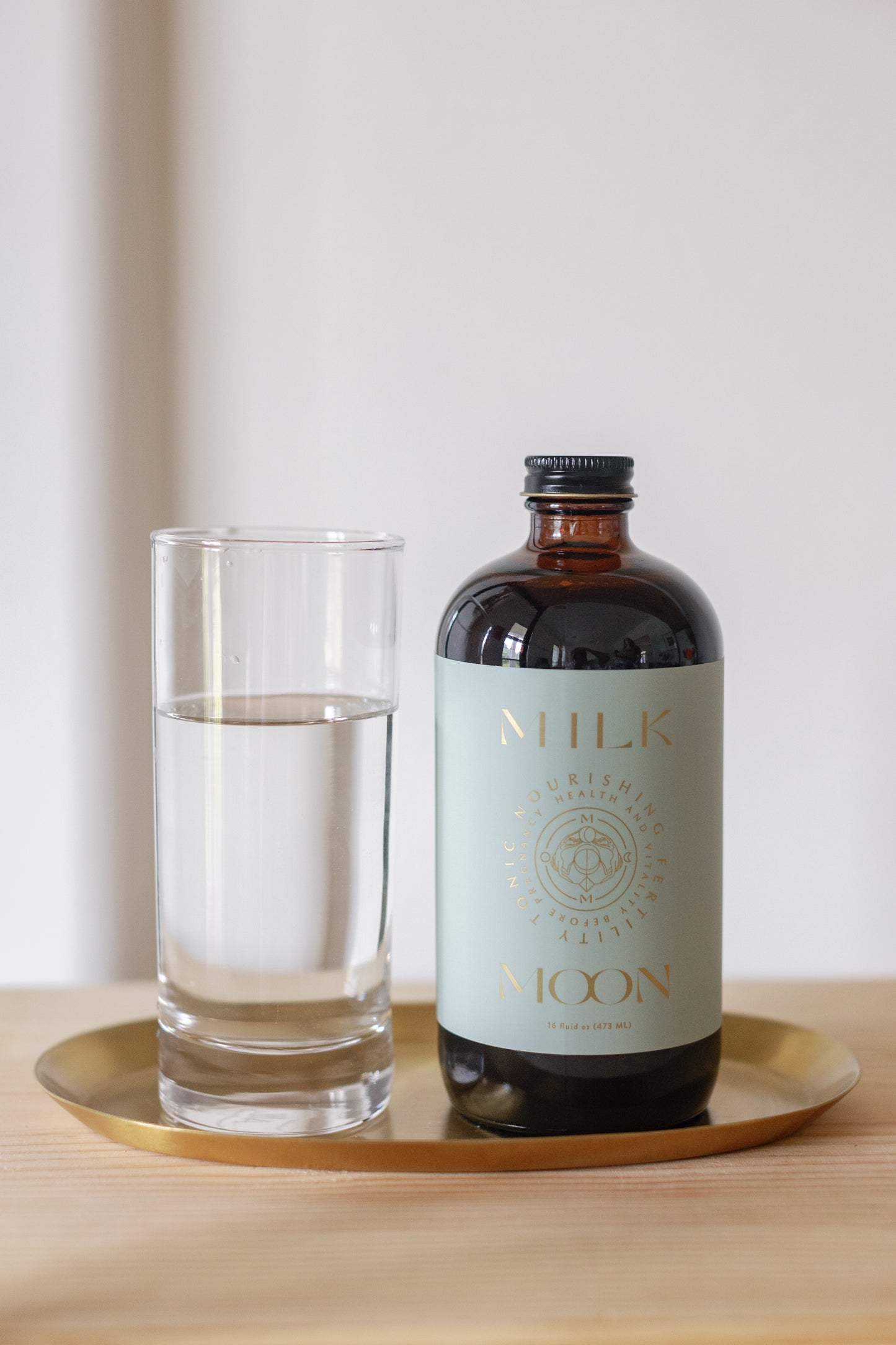 Picture of the open Nourishing Fertility Tonic bottle with a full glass on it's side