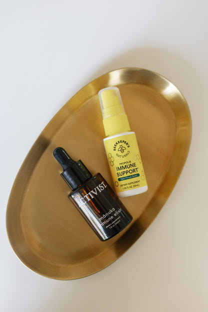 Picture of the Propolis Throat Spray and the Manuka Immune Elixir on a golden plate
