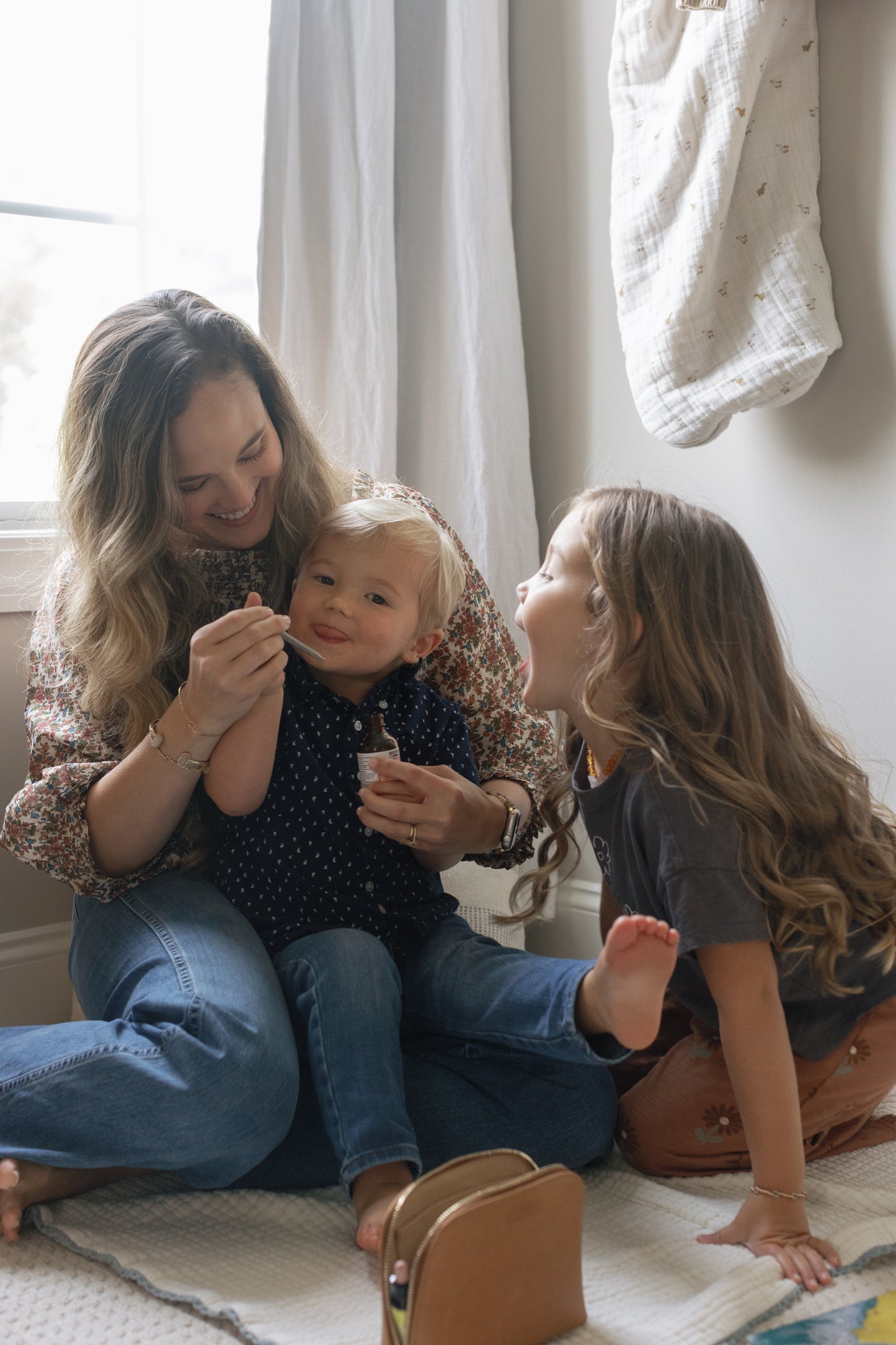 Image of Caroline and her two small children playing with the dropper of the NDF Tummy