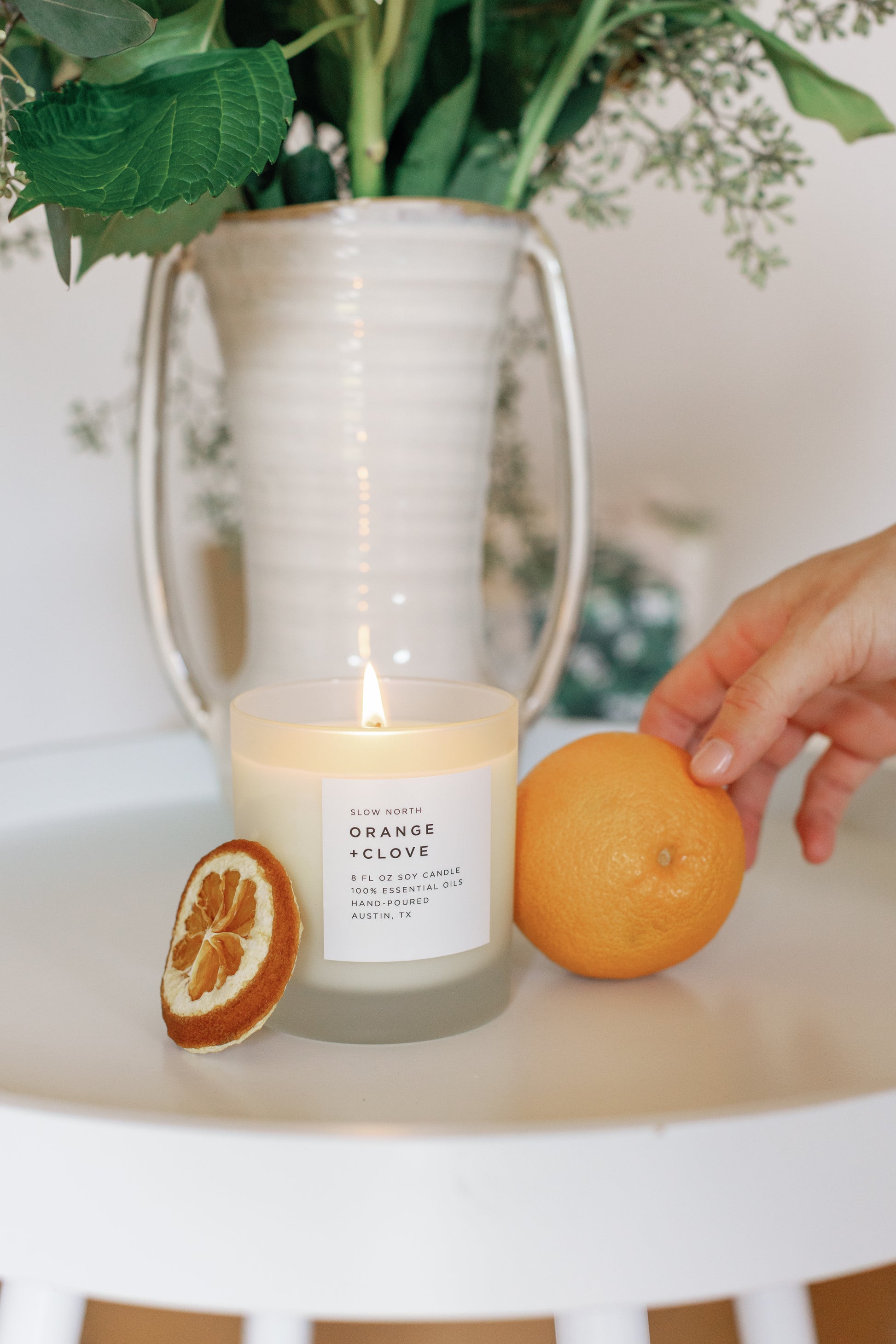 Image of the lit Orange Clove Candle and a orange on it's side