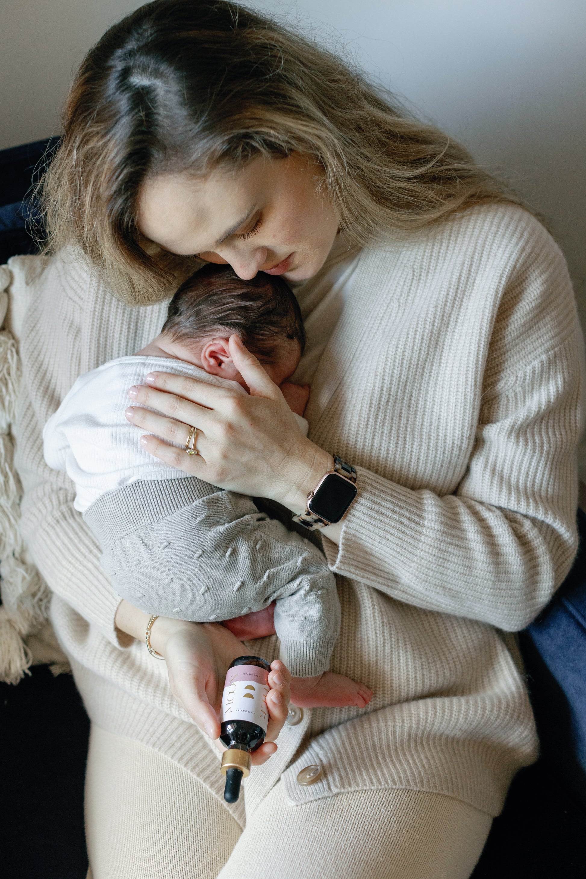 Image of Caroline calming her baby and holding the No Worries Tonic
