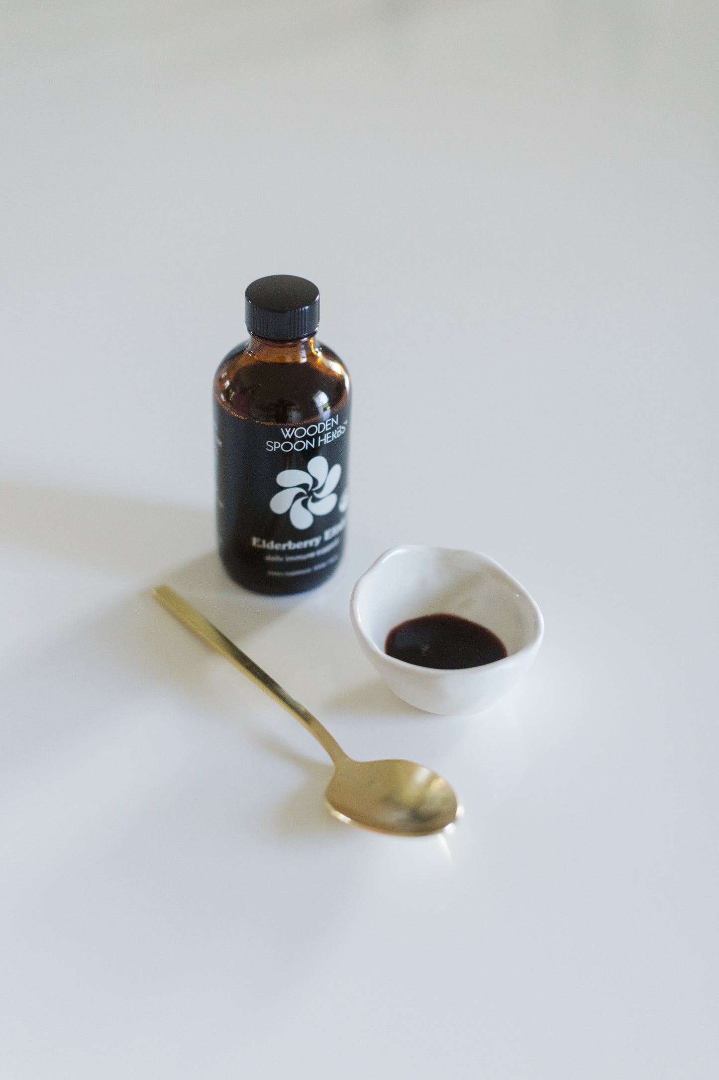 A bottle of Elderberry Elixir by Wooden Spoon Herbs sitting on a table.