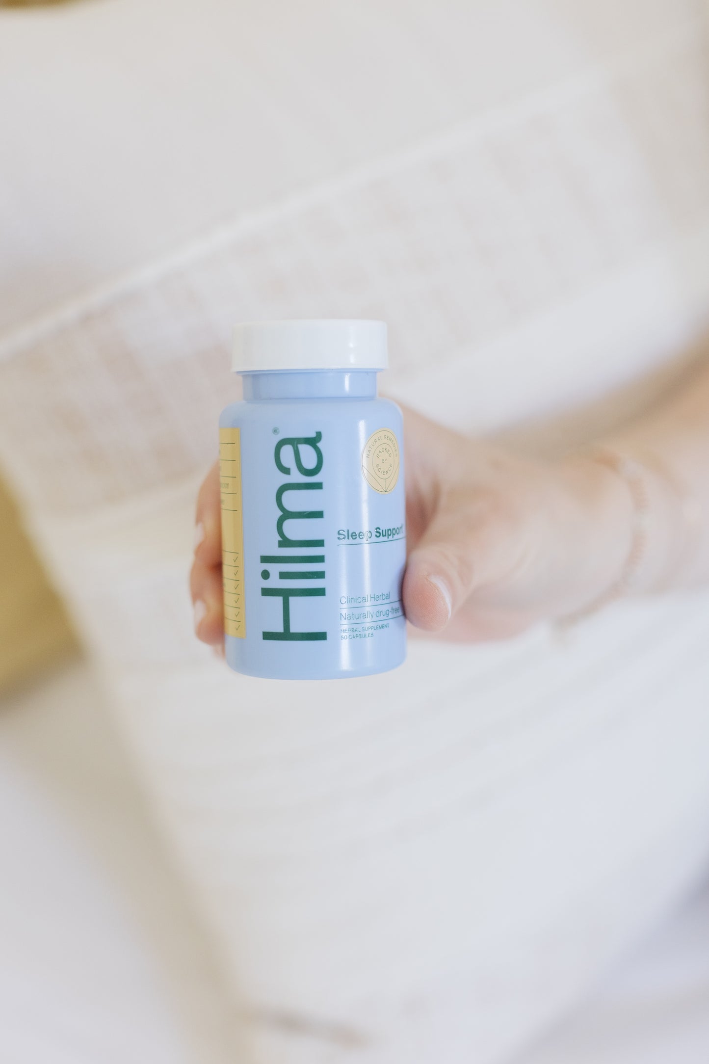 Caroline holding a bottle of Hilma Sleep Support