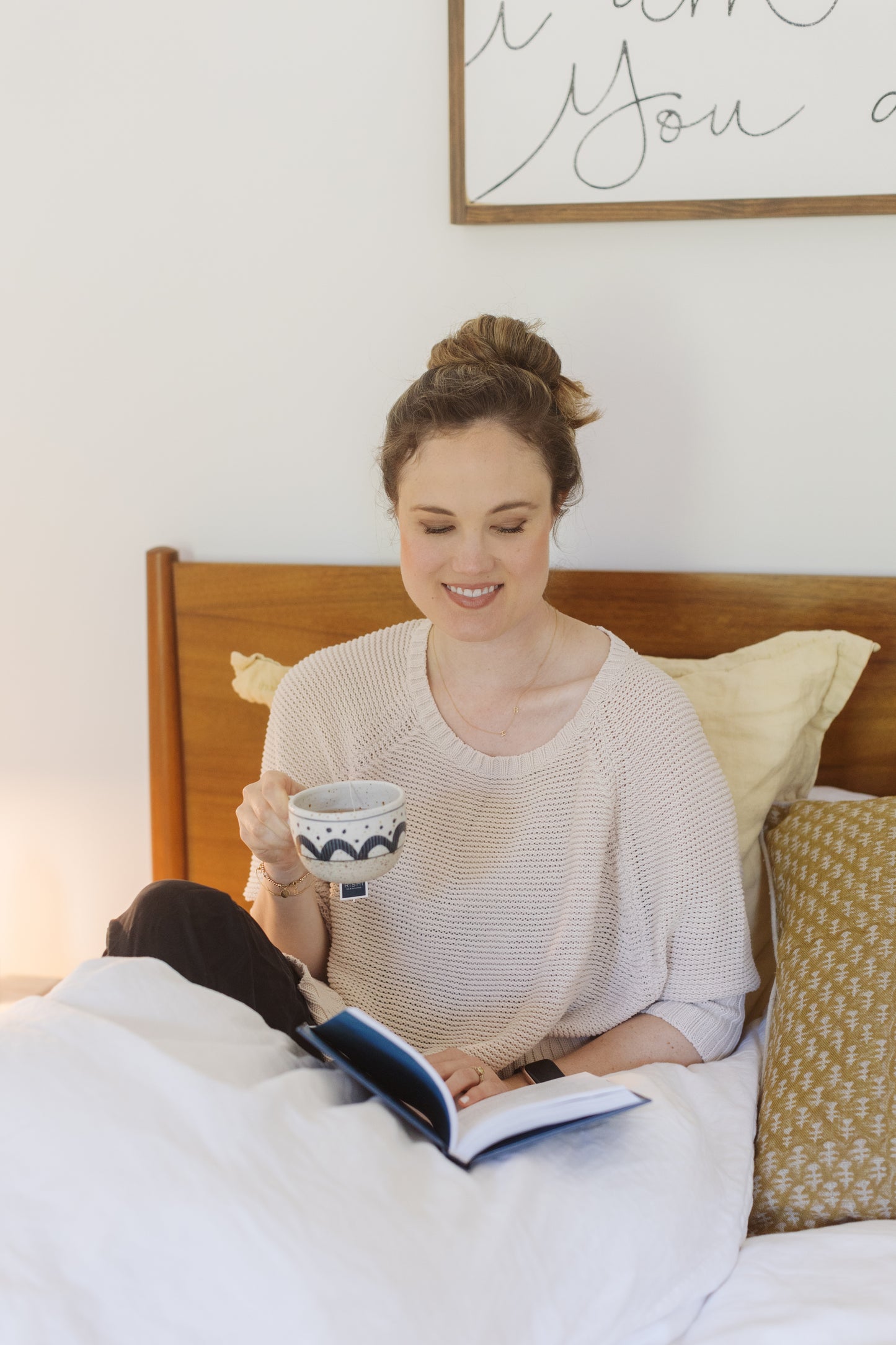 picture of a night stand with a cup of tea, a sleep support and a magnesium lotion on top of it